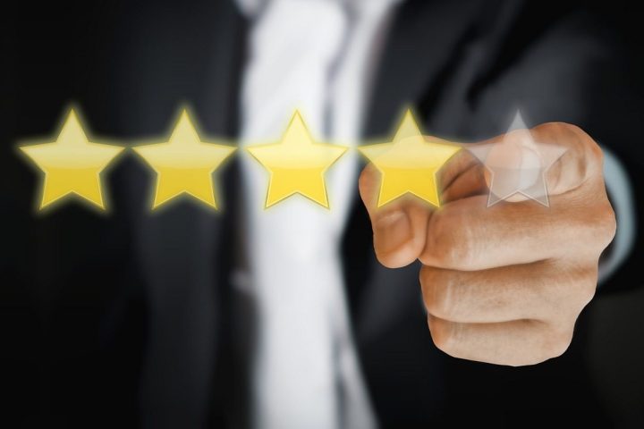 Main qui désigne une note en étoiles dorées pour évaluer un service