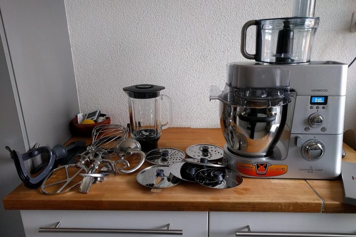 Robot cuiseur Kenwood Cooking Chef posé sur un plan de travail avec ses accessoires
