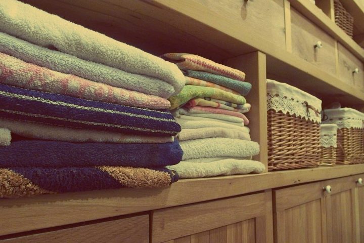 Piles de linge plié rangées sur les étagères d'un placard en bois avec paniers