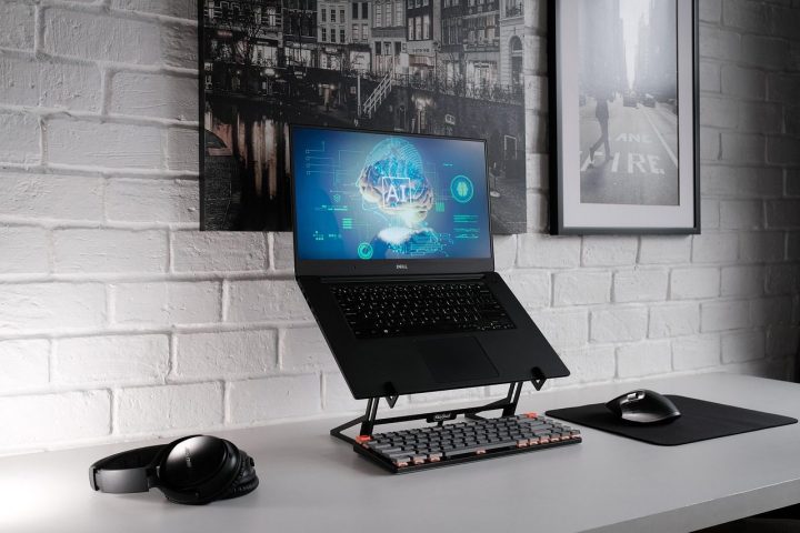 Ordinateur portable sur support, souris et casque sur un bureau blanc