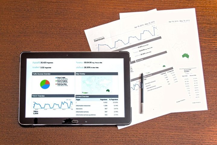 Tablette affichant des graphiques de suivi, posée sur des rapports papier
