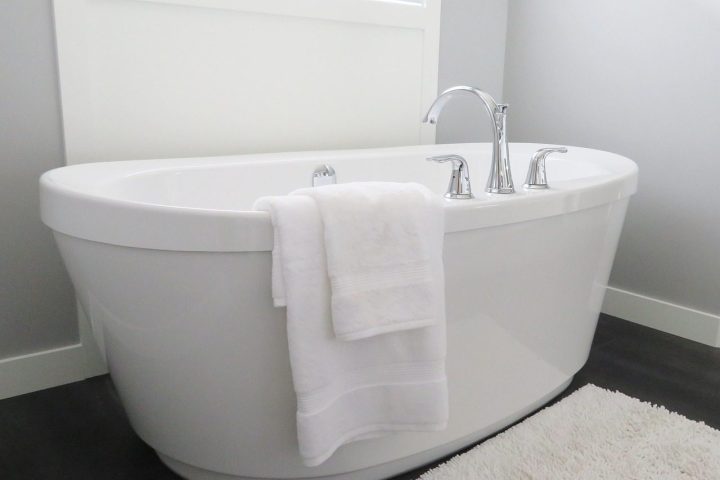 Salle de bain blanche avec baignoire îlot et tapis de bain posé au sol