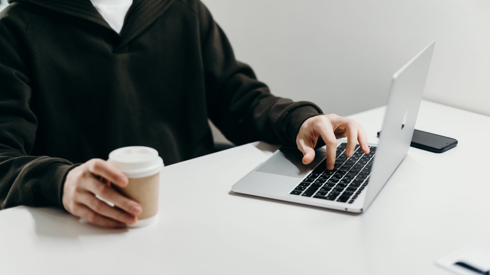 Indépendant devant son ordinateur portable avec un café, en train de lister ses tâches répétitives
