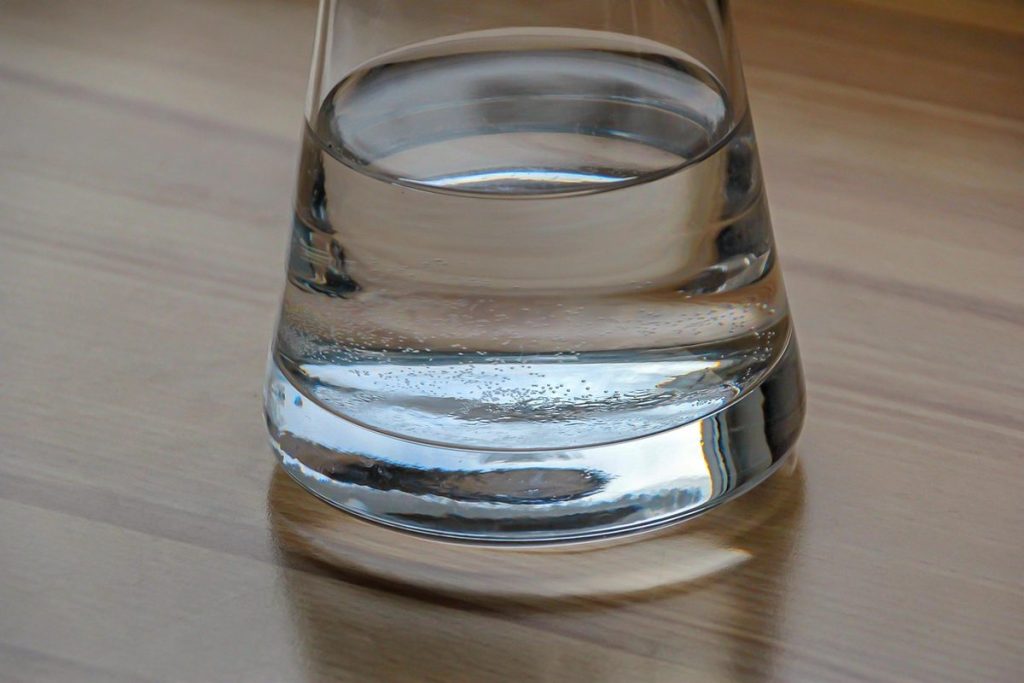 Un verre d'eau posé sur une table en bois