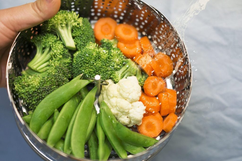 Panier en inox rempli de brocolis, de carottes, de petits pois et de chou-fleur