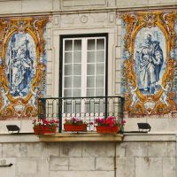 Façade de maison à Lisbonne ornée de panneaux d'azulejos autour d'un balcon fleuri