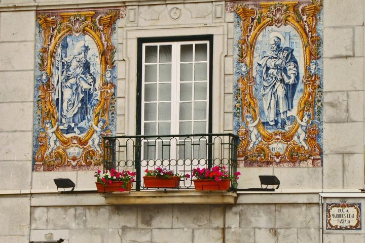 Façade de maison à Lisbonne ornée de panneaux d'azulejos autour d'un balcon fleuri