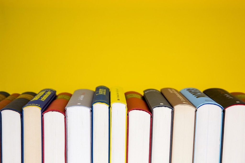 Rangée de livres de couleurs différentes sur fond jaune