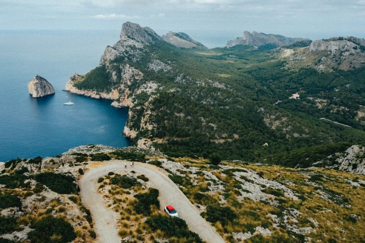 Une voiture sur une route en lacets au-dessus de la mer, dans un paysage de falaises