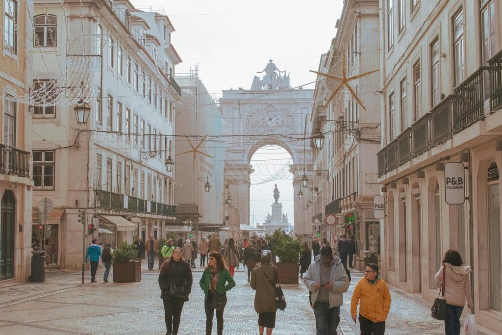 Une rue commerçante piétonne de Lisbonne avec des habitants qui marchent, l'arc de la Rua Augusta au fond