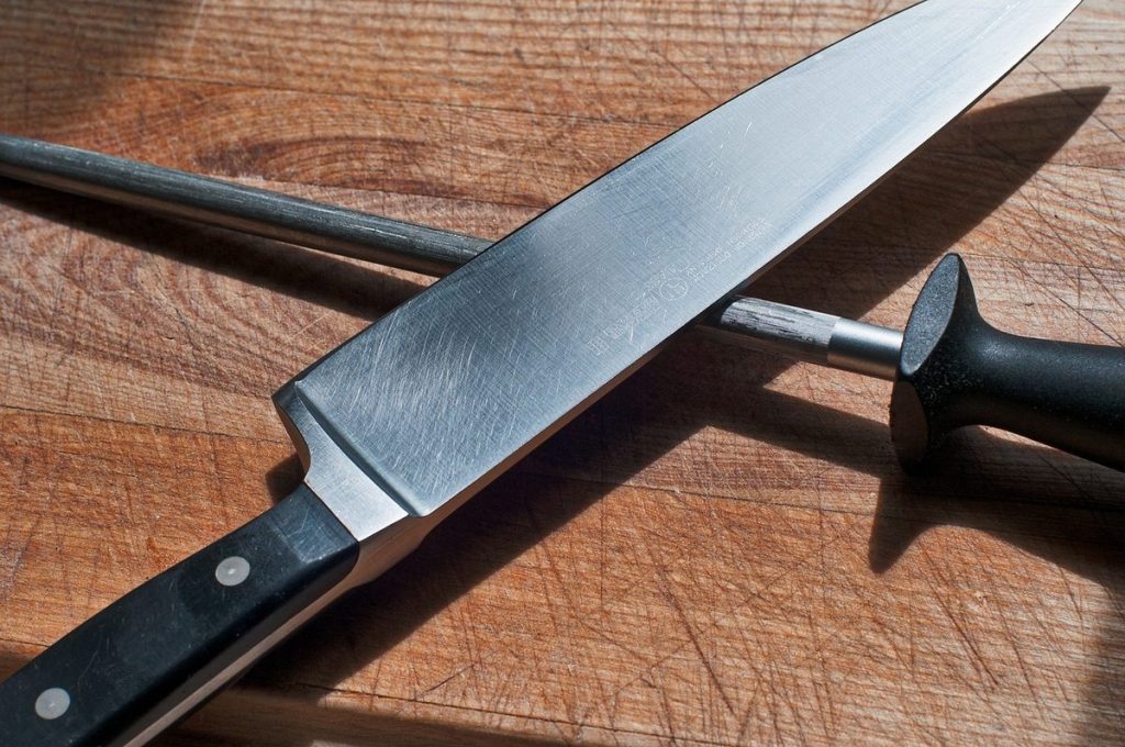 Couteau de chef et fusil à aiguiser posés sur un plan de travail en bois