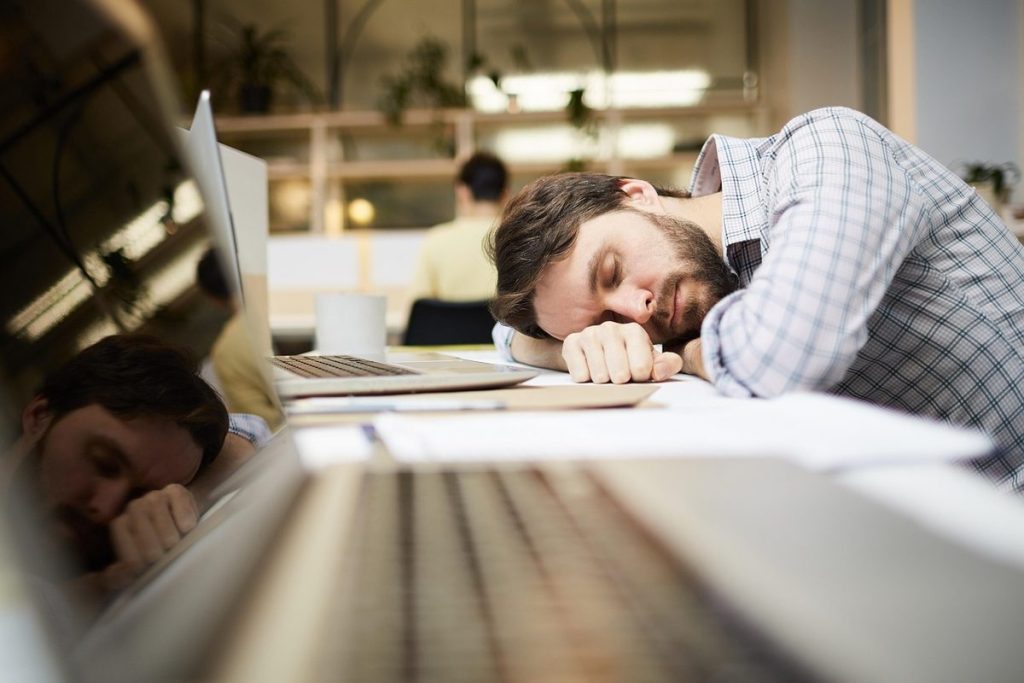 Un salarié qui se repose la tête posée sur son bureau, devant son ordinateur portable