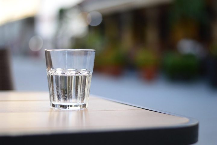 Verre d'eau posé sur une table de terrasse